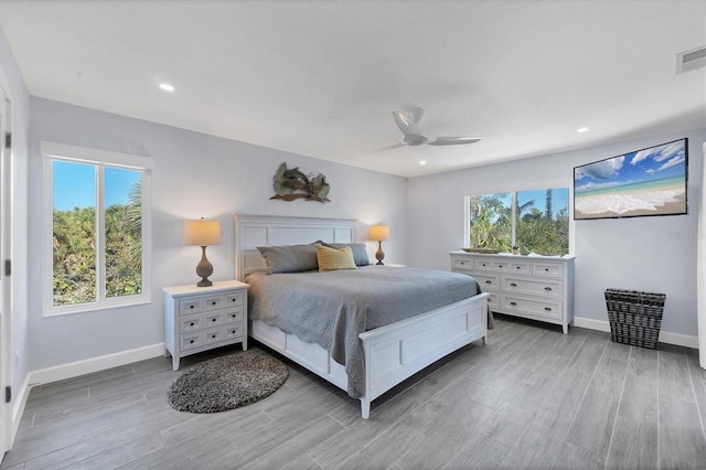 bedroom with ceiling fan, wood-type flooring, and multiple windows