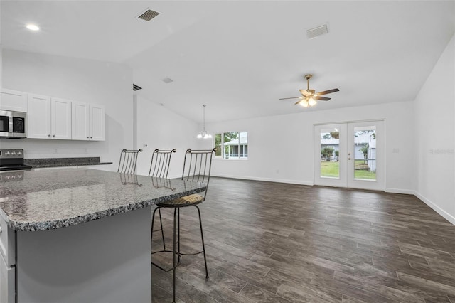 kitchen with electric range, a breakfast bar, dark hardwood / wood-style floors, white cabinetry, and stone countertops