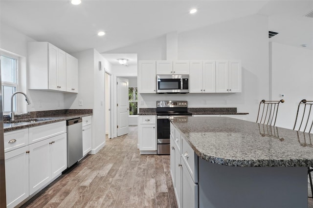 kitchen with a kitchen island, stainless steel appliances, sink, and white cabinetry