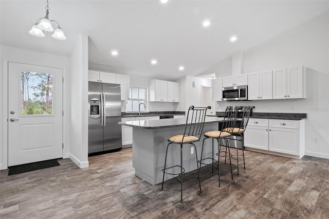 kitchen featuring a kitchen breakfast bar, appliances with stainless steel finishes, a kitchen island, white cabinetry, and decorative light fixtures