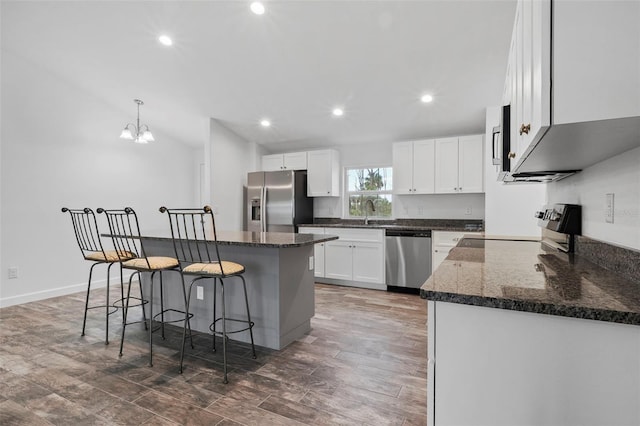 kitchen with appliances with stainless steel finishes, a center island, white cabinets, and decorative light fixtures