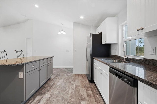 kitchen with stainless steel appliances, decorative light fixtures, white cabinetry, and dark stone countertops