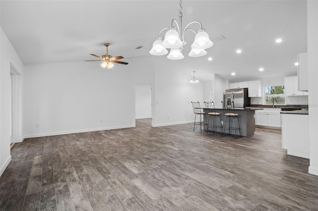 unfurnished living room featuring ceiling fan with notable chandelier, sink, and dark wood-type flooring