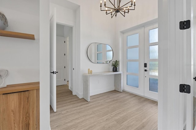 entrance foyer with a chandelier, light hardwood / wood-style flooring, and french doors