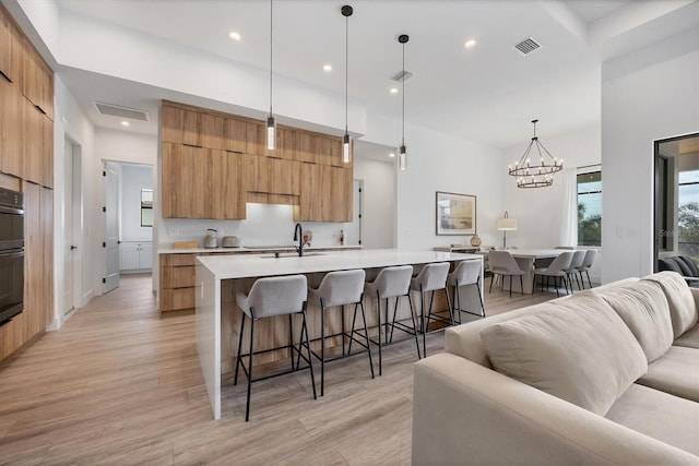 kitchen featuring a kitchen breakfast bar, light wood-type flooring, a large island, and decorative light fixtures