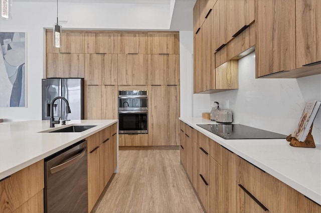 kitchen featuring light wood-type flooring, appliances with stainless steel finishes, sink, and pendant lighting