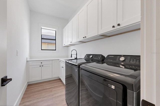 laundry area with cabinets, light hardwood / wood-style floors, washer and clothes dryer, and sink