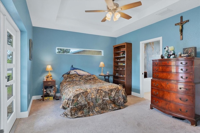 bedroom with ceiling fan, light colored carpet, a tray ceiling, and multiple windows