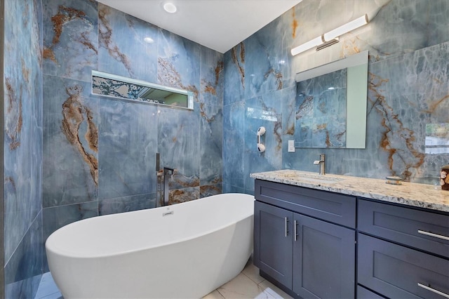 bathroom featuring a tub, tile walls, tile patterned floors, and vanity