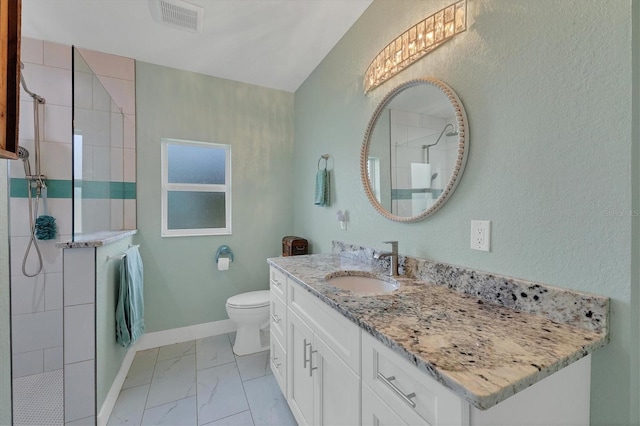 bathroom with toilet, a tile shower, and vanity