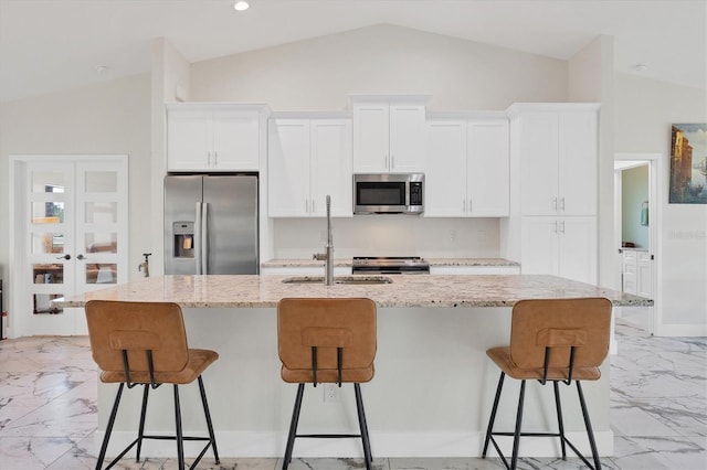 11247 Euler Ave, Englewood, FL 34224 - kitchen with stainless steel appliances, vaulted ceiling, light marble finish floors, a sink, and white cabinetry