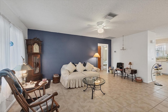 bedroom with ceiling fan, light tile patterned flooring, and a textured ceiling