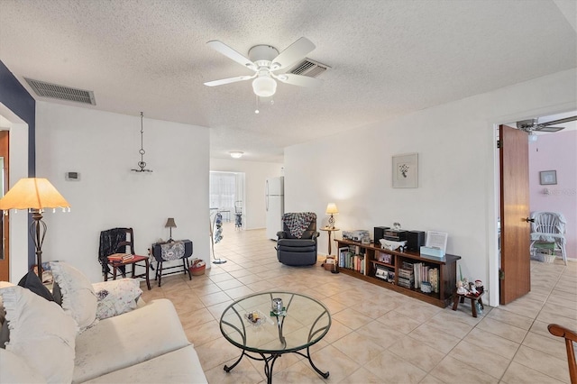 tiled living room with ceiling fan and a textured ceiling