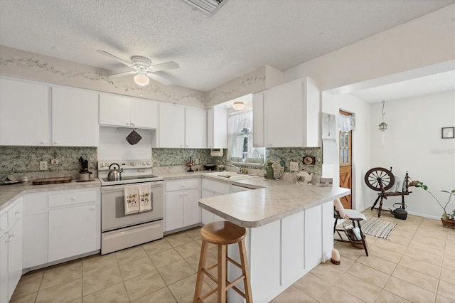 kitchen featuring kitchen peninsula, white electric range oven, a textured ceiling, sink, and white cabinetry