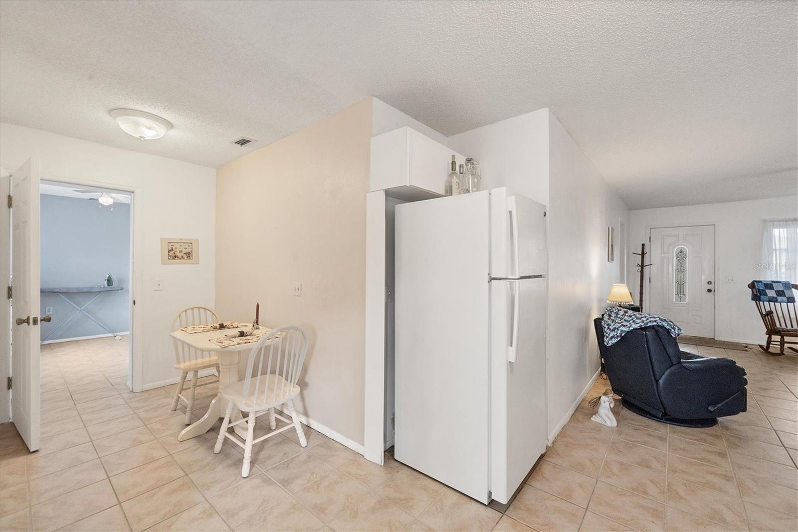 kitchen with white cabinets, white fridge, light tile patterned floors, and a textured ceiling