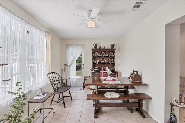 dining area with ceiling fan, light tile patterned floors, and a textured ceiling