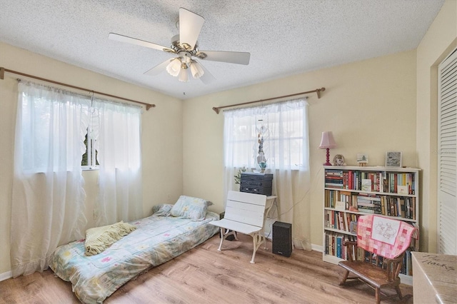 bedroom with a textured ceiling, light hardwood / wood-style flooring, and ceiling fan