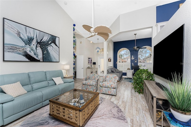 living room with ceiling fan, wood-type flooring, and high vaulted ceiling