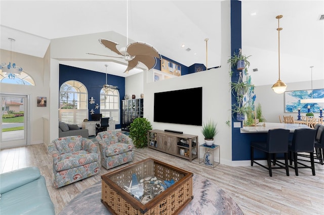 living room with ceiling fan, light hardwood / wood-style floors, and high vaulted ceiling