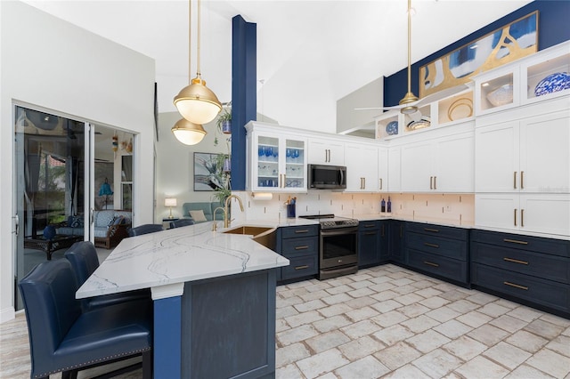 kitchen featuring kitchen peninsula, appliances with stainless steel finishes, a breakfast bar, decorative light fixtures, and white cabinets