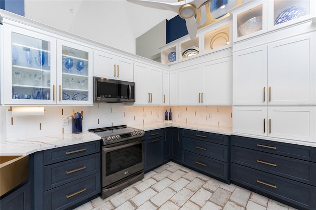 kitchen with backsplash, stainless steel appliances, white cabinetry, and light stone counters