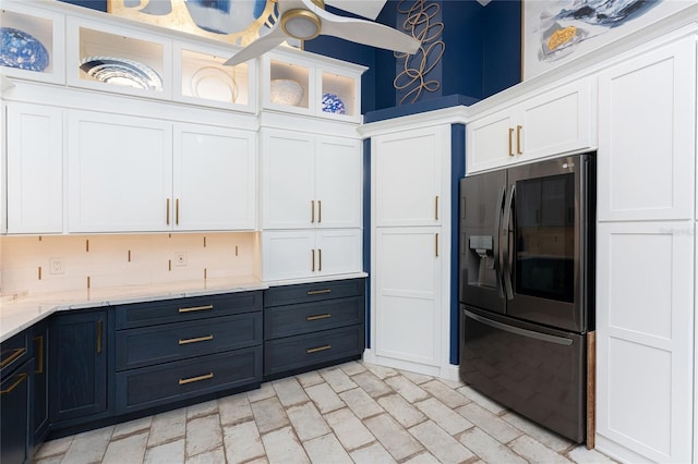 kitchen featuring refrigerator with ice dispenser, backsplash, white cabinetry, and light stone countertops