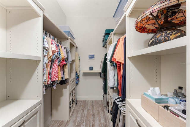 walk in closet with light hardwood / wood-style flooring