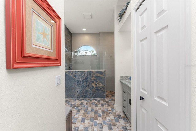 bathroom featuring tiled shower and vanity