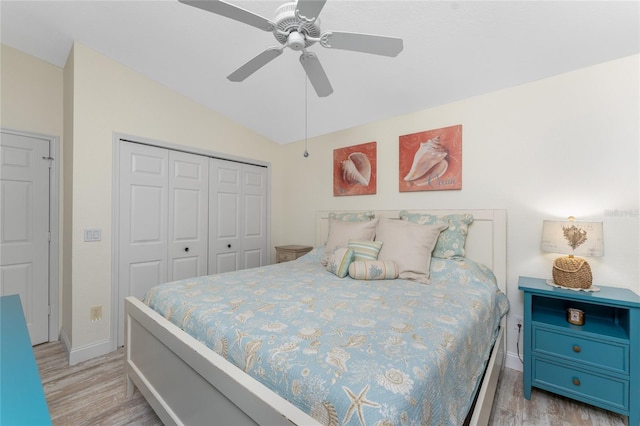 bedroom featuring light wood-type flooring, a closet, vaulted ceiling, and ceiling fan