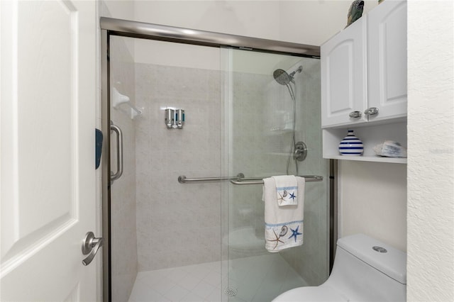 bathroom featuring a shower with shower door and toilet