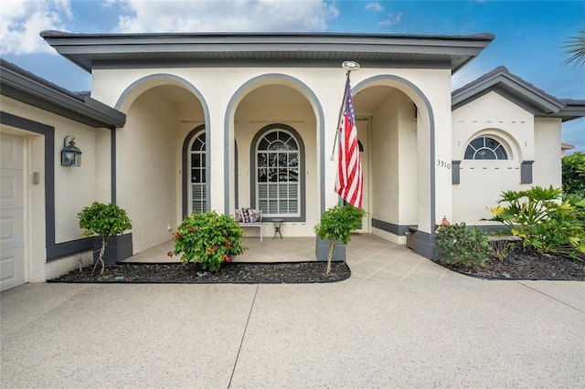 view of exterior entry featuring a porch and a garage