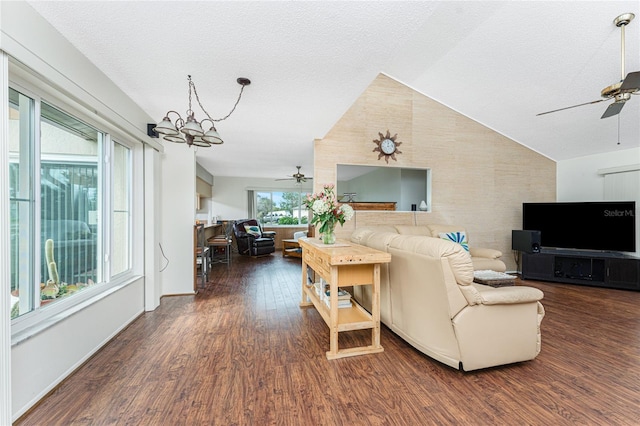 living room featuring lofted ceiling, dark hardwood / wood-style flooring, ceiling fan with notable chandelier, and a textured ceiling