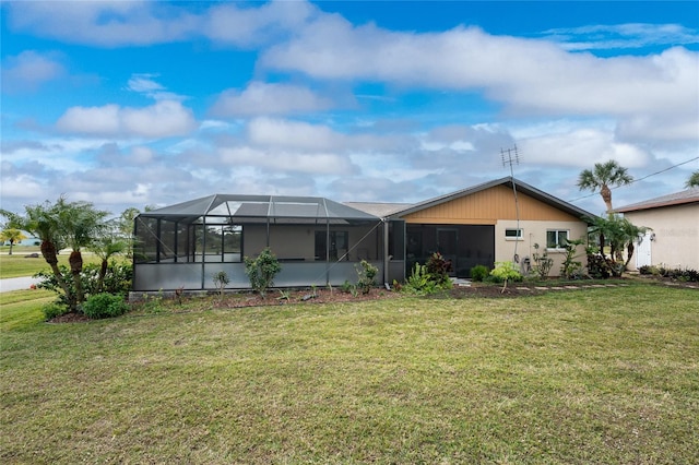 rear view of house with glass enclosure and a lawn