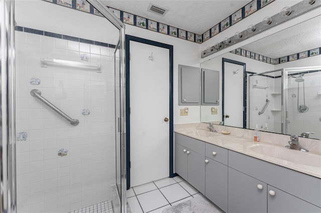 bathroom with tile patterned flooring, an enclosed shower, vanity, and a textured ceiling