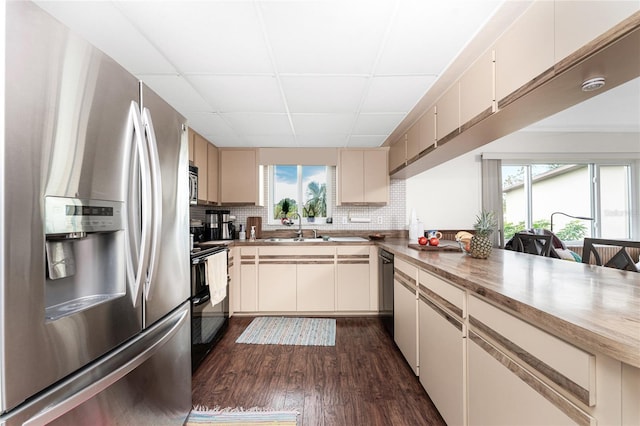 kitchen with sink, tasteful backsplash, appliances with stainless steel finishes, cream cabinets, and a drop ceiling