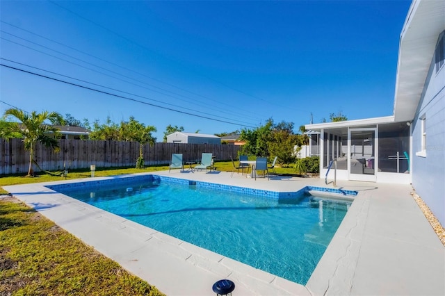 view of swimming pool with a sunroom, a lawn, and a patio