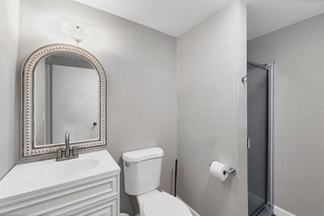 bathroom featuring toilet, vanity, and a shower with shower door