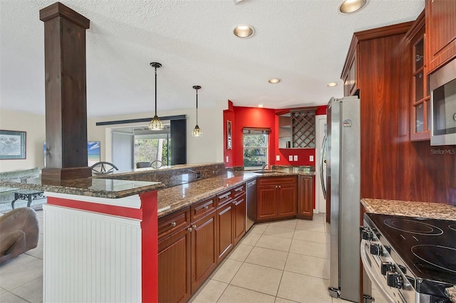 kitchen with sink, hanging light fixtures, dark stone countertops, light tile patterned floors, and appliances with stainless steel finishes