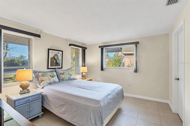 bedroom with multiple windows, light tile patterned floors, and a textured ceiling