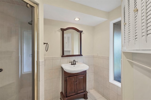 bathroom with vanity, a shower with door, and tile walls