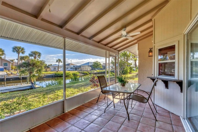 sunroom featuring a water view, a wealth of natural light, lofted ceiling, and ceiling fan