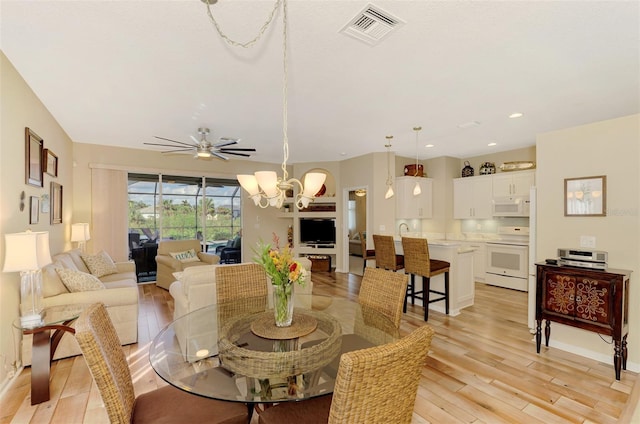 dining area featuring ceiling fan with notable chandelier and light hardwood / wood-style flooring