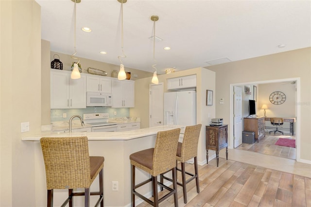 kitchen featuring kitchen peninsula, backsplash, white appliances, pendant lighting, and white cabinets