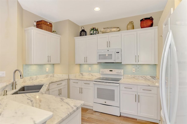 kitchen featuring white cabinets, white appliances, light stone countertops, and sink