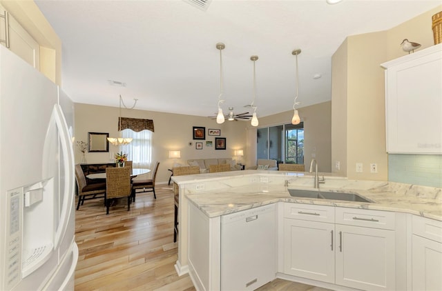 kitchen with sink, kitchen peninsula, white appliances, white cabinets, and ceiling fan with notable chandelier