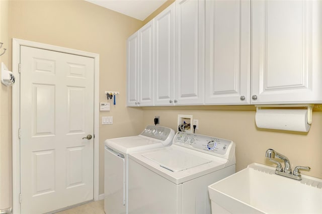 clothes washing area featuring washing machine and dryer, sink, and cabinets