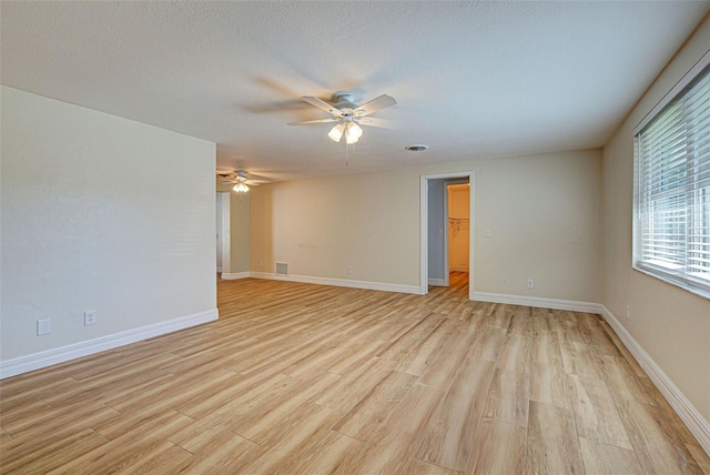 empty room with ceiling fan, light hardwood / wood-style flooring, and a textured ceiling