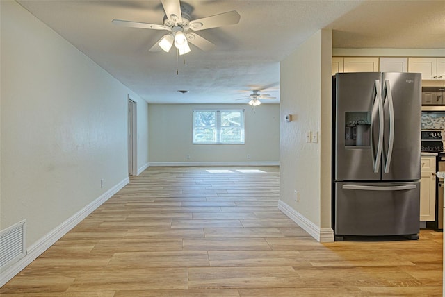 kitchen with white cabinetry, backsplash, stainless steel fridge, and ceiling fan