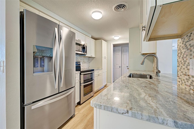 kitchen featuring decorative backsplash, sink, white cabinetry, and stainless steel appliances