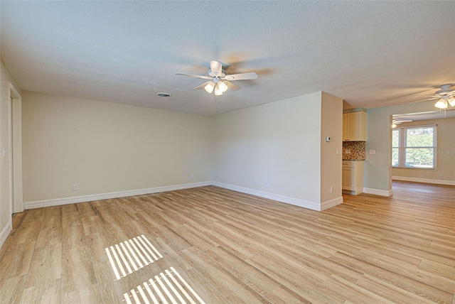 empty room with a textured ceiling, light hardwood / wood-style floors, and ceiling fan